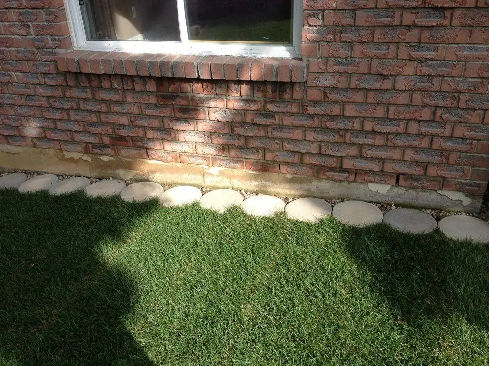 Lawn with rounded stone edging beside a brick house